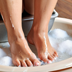 **Foot care preparation:** A person soaking their feet in warm water with shampoo, salt, and essential oils, preparing for a foot file treatment. The scene should be relaxing and show the foot soaking process clearly.
